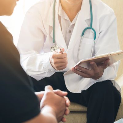 Doctor consulting with patient holding a clipboard.