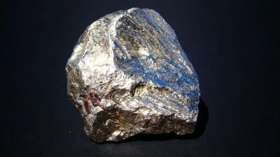 A shiny silver rock against a black background.