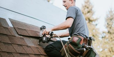 Worker installing shingles on a roof.