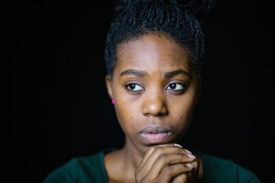 A thoughtful young woman looking away with clasped hands.