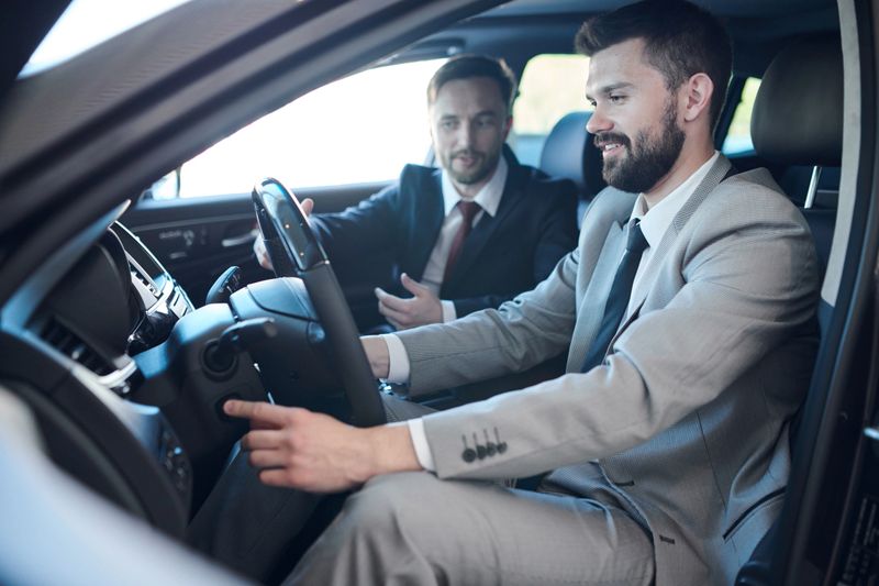 Side view portrait of mature bearded businessman sitting inside brand new car in dealership showroom taking it for test drive