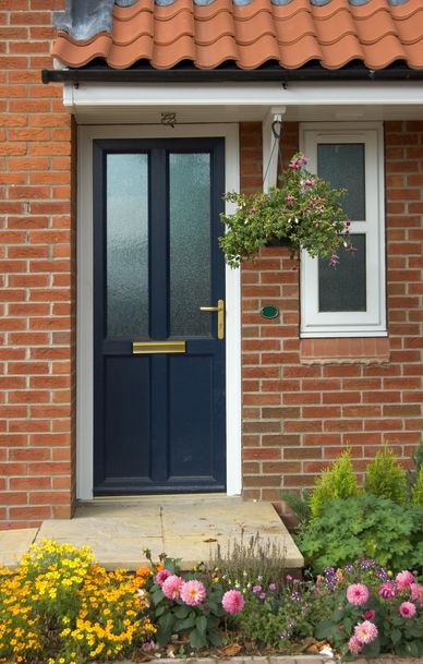 Blue front door with hanging flower basket and colorful garden.