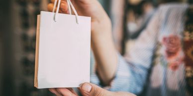 Person holding a plain white paper bag.