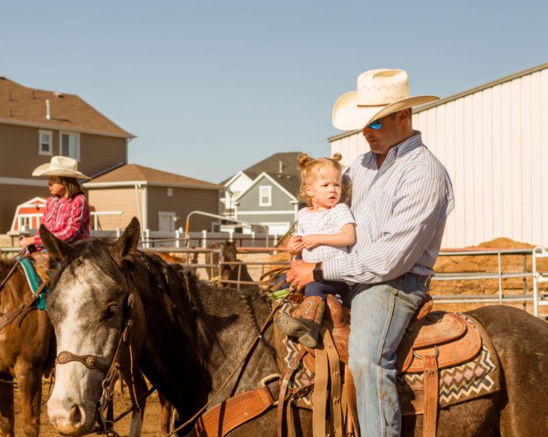 Cowboy with baby daughter riding horse at ranch in Salt lake City SLC Utah USA