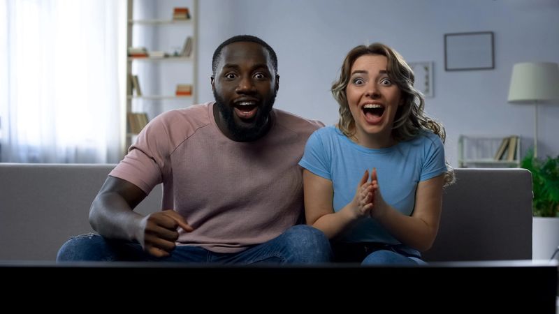 Couple watching sports match on tv home, celebrating victory, successful game