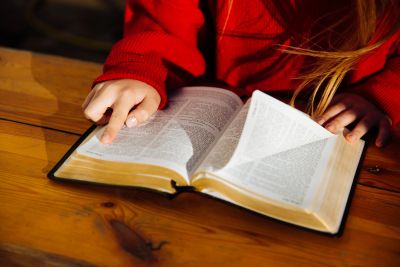 Child reading a book with a finger on the page.