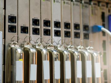 Row of metallic fire extinguishers in front of network equipment.