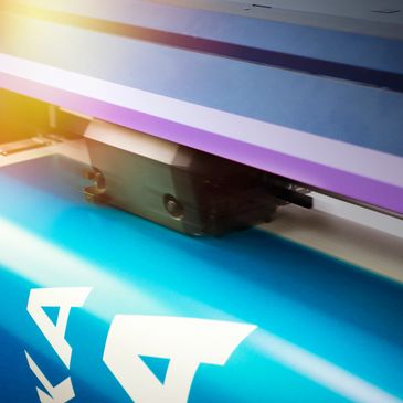 Close-up of a large-format printer printing a blue banner.