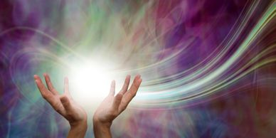 Hands holding a glowing light with colorful swirling background.