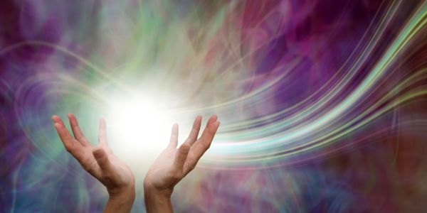 Hands holding a glowing light with colorful swirling background.