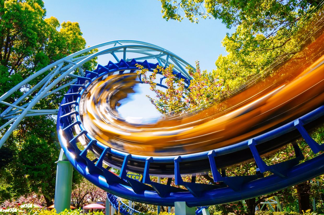 A roller coaster speeding through a loop surrounded by trees.