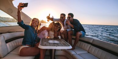 Group of friends taking a selfie on a boat at sunset.