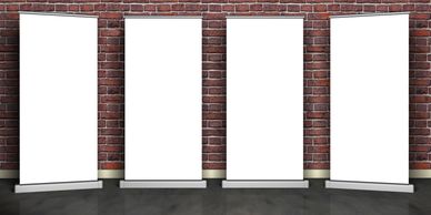 Four blank vertical banner stands against a brick wall on a reflective floor.