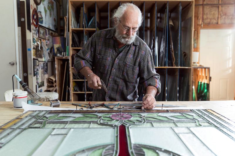 High quality stock photo of an active senior in his stained glass art studio.