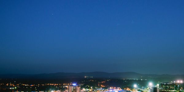 Cityscape at night under a clear blue sky.