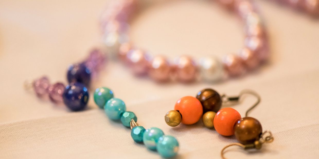 Close-up of hands crafting beaded jewelry with rings.