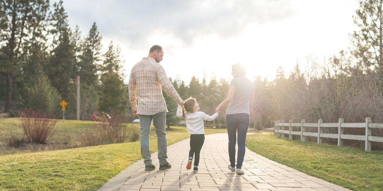 Family walking hand-in-hand on a sunny path.