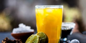 A glass of refreshing orange juice with lemon halves and spices.