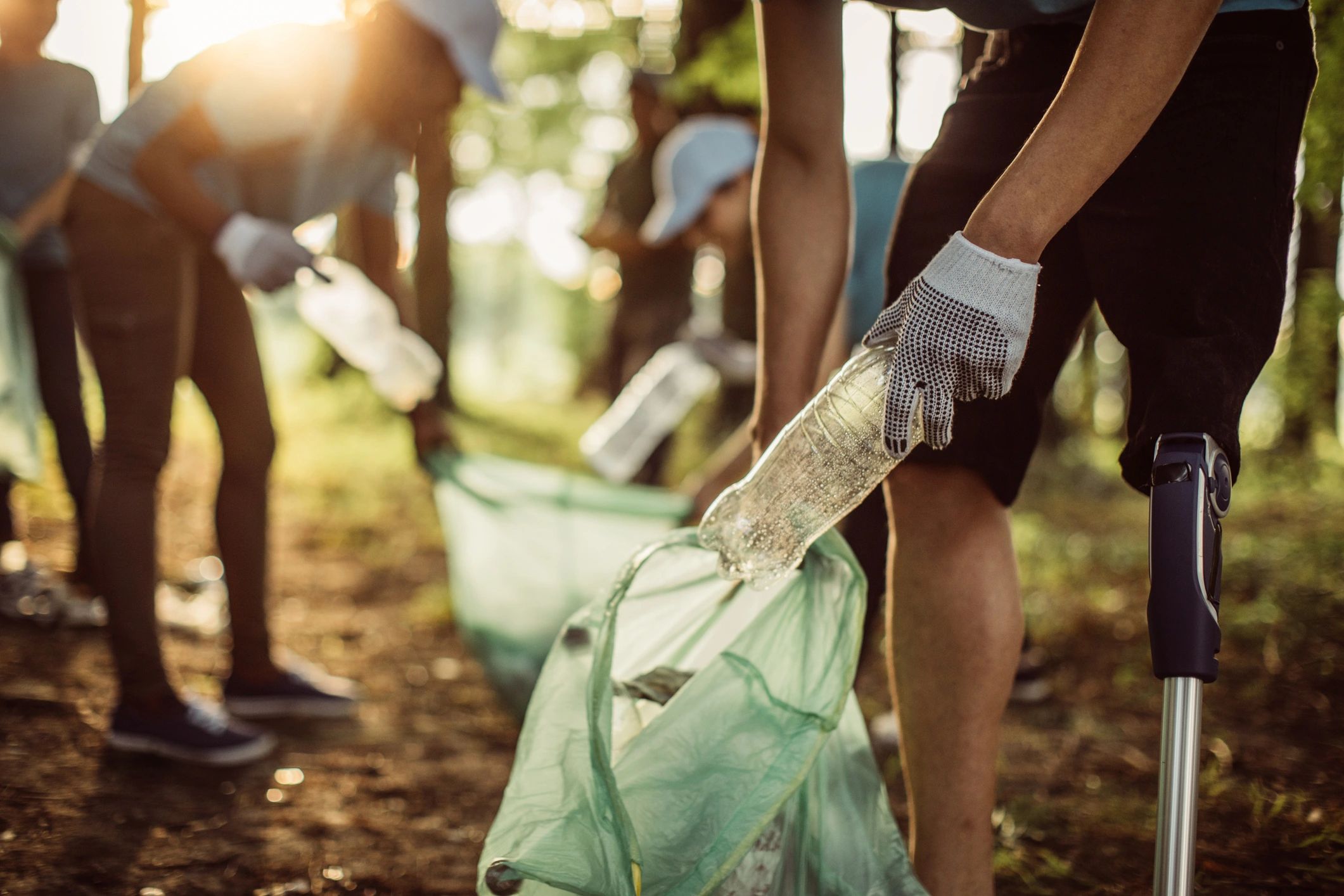 Volunteers picking up litter outdoors with gloves and bags.