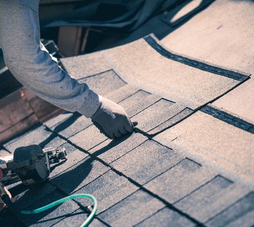 A brick wall with a sealed roof junction featuring gray shingles and metal flashing.