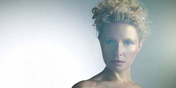 Portrait of a woman with curly hair and blue eyes.