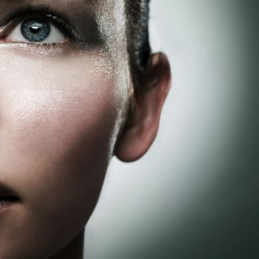 Close-up of a woman's face with glittery makeup and blue eye.