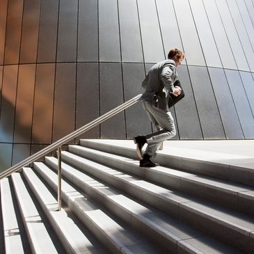 Businessman in a suit running up stairs with briefcase.