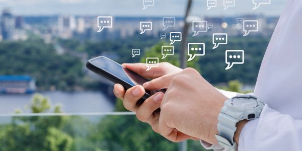 Person using smartphone with chat icons floating.