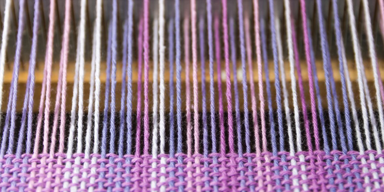 Close-up of colorful threads on a loom.