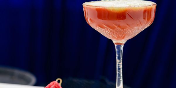 Cocktail in a decorative glass with a garnish on a wooden board.