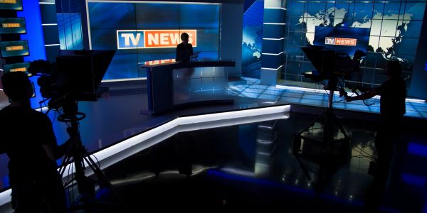 Plateau de télévision avec silhouette de présentateur et caméras.