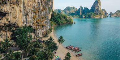 Scenic tropical beach with cliffs and boats.