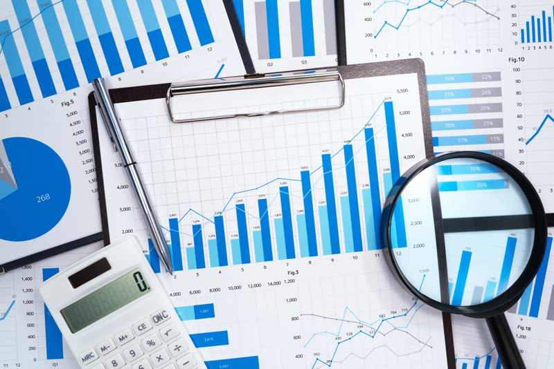 Many business reports. Magnifying glass,calculator and pen.