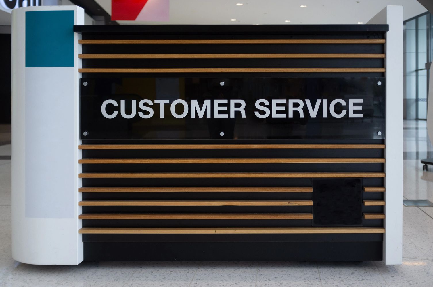 Modern customer service desk with wood paneling and bold signage.