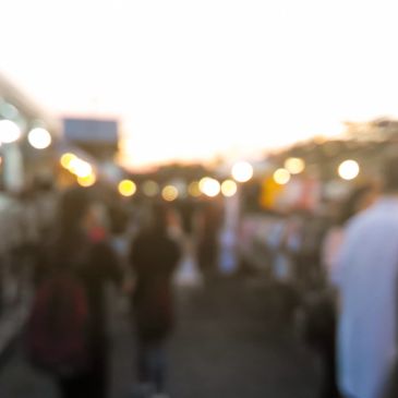 Blurred image of people in an outdoor setting at dusk.
