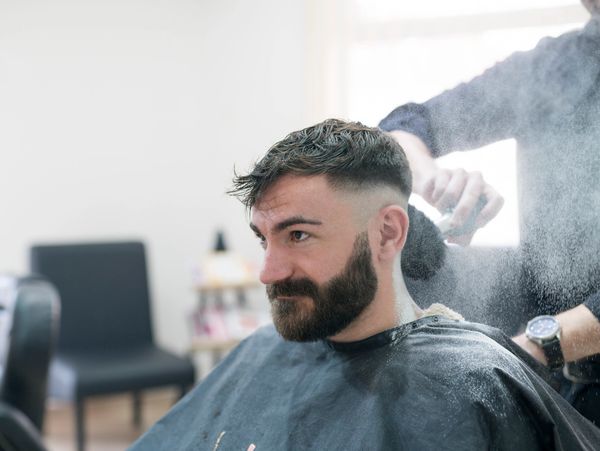 Side profile of a man with a fresh crew cut haircut featuring shaved designs and a skin fade.