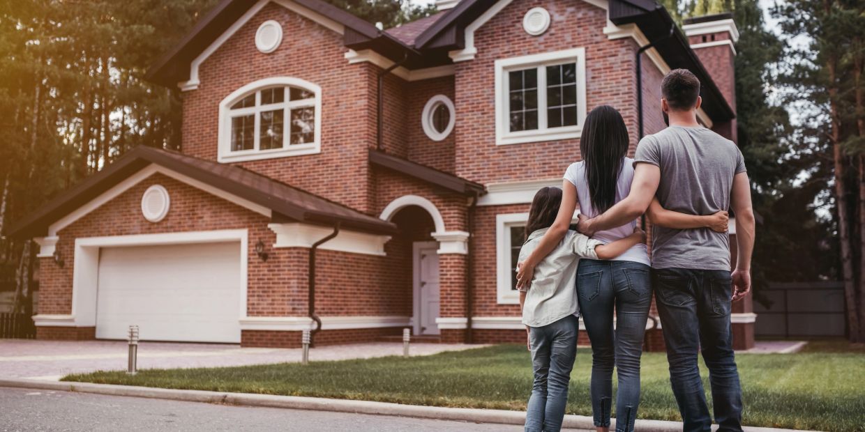 Family admiring their new brick house.