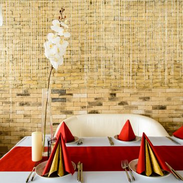 Elegant dining table with red and gold napkins and white orchid centerpiece.
