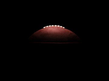 Half-lit American football on a dark background.