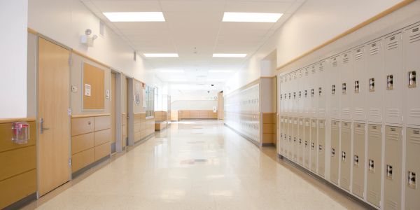 Empty school hallway with lockers and classroom doors.