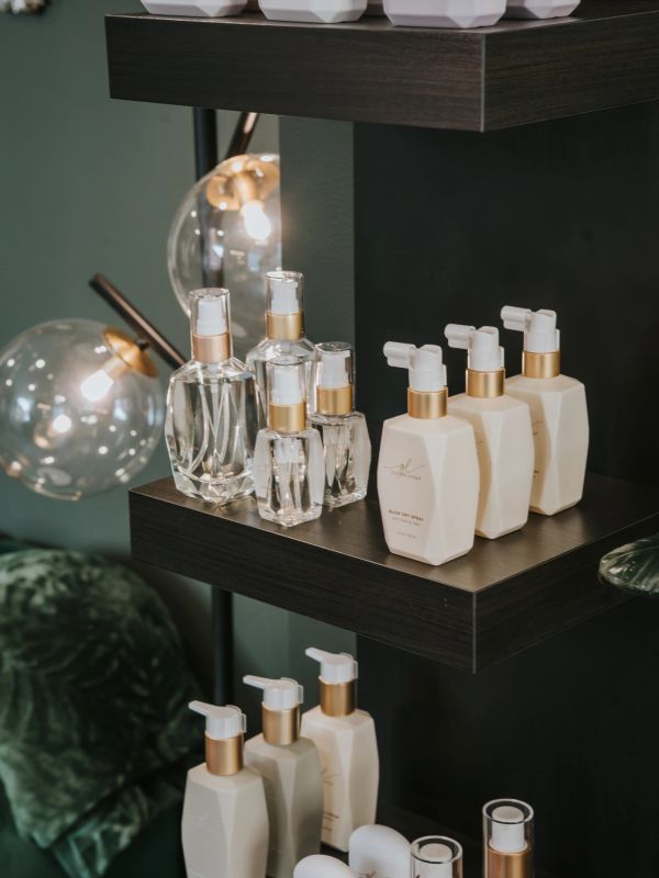 Elegant skincare bottles with gold accents displayed on dark wooden shelves.