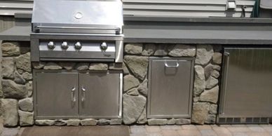Outdoor kitchen setup with stainless steel grill and storage.