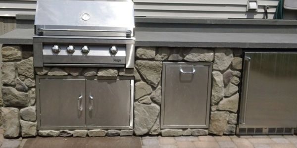 Outdoor kitchen setup with stainless steel grill and storage.