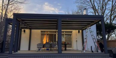 Modern black pergola on a porch at sunset.