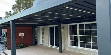 Modern patio cover with retractable roof attached to house.