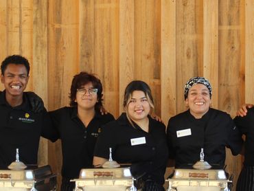 Catering staff standing behind a buffet table with chafing dishes.