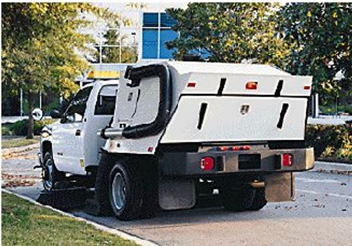White utility truck with a large rear storage compartment parked by the curb.