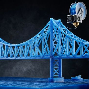 3D printer creating a detailed blue bridge model with a small boat.