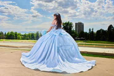 Mujer con vestido azul estilo princesa en un parque.