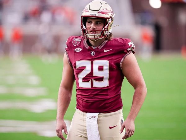 Football player in maroon and gold uniform standing on the field.